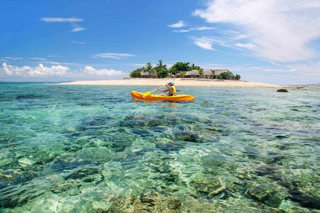 Young woman kayaking near South Sea Island, Mamanuca islands group, Fiji. 