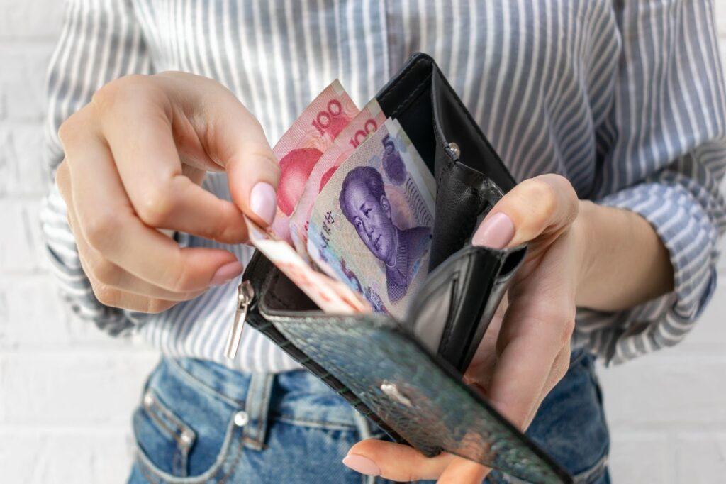 Asian womans hand takes out Chinese yuan banknotes from her wallet.